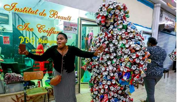 A woman dances next to a participant dressed in a costume made of cans during the celebrations marking the 60th anniversary of Congou2019s independence from Belgium in the Brussels district of Matonge, yesterday.