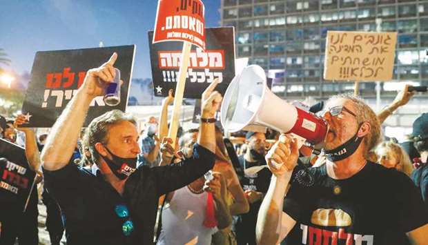 Israelis lift placards and chant slogans during a demonstration in Rabin Square in Tel Aviv yesterday, to protest the governmentu2019s abandonment of the countryu2019s self-employed and other sectors after forcing their businesses to close under Covid-19 regulations, according to the organisers.
