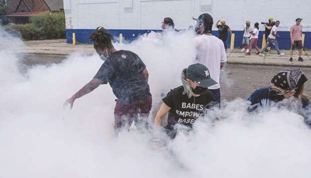 Protesters attempt to put out a tear-gas canister fired by Detroit police to disperse demonstrators during a march at the West Side on Friday, where 20-year-old Hakeem Littleton was shot and kailled by a policeman earlier in the day. Video footage released by Police Chief James Craig, within hours of the shooting, appeared to show Littleton firing a gun at an officer from close range before being shot. Anti-police brutality protesters have been marching in Detroit nearly everyday since the May 25, 2020, death of George Floyd at the hands of a white Minneapolis police officer.