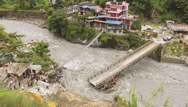 People gather near the bridge that is damaged due to the flood at Raghu Ganga River in Myagdi, yesterday.