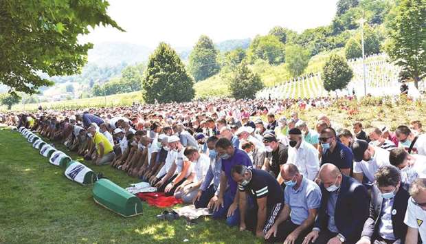 Bosnian Muslims wearing face masks pray during a burial ceremony yesterday at the Potocari memorial cemetery, a village just outside Srebrenica.