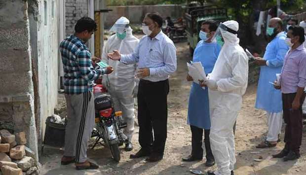 Health officials wearing Personal Protective Equipment (PPE) collect medical records from residents before taking samples for coronavirus during a door-to-door screening and testing operation at a slum area in Islamabad yesterday.