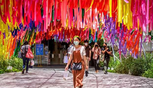 A woman wearing a face mask walks out of a shopping mall in Bangkok
