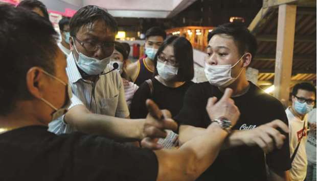 A pro-Beijing activist (left) hurls insults at Roy Tam Hoi-pong and his volunteer during a campaign for the primary election aimed at selecting democracy candidates for the September election, in Hong Kong.