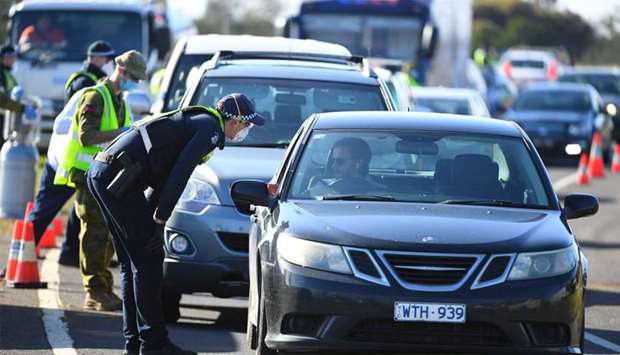A Victoria Police officer works at a vehicle checkpoint created in response to an outbreak of COVID-19 near Melbourne