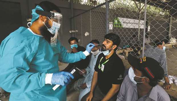 A paramedic wearing protective gear takes a nasal swab from a man, to be tested for the coronavirus disease (Covid-19), in Karachi yesterday.