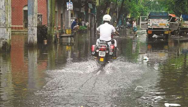 A policeman rides a motorbike through a waterlogged road after heavy rains in Kolkata yesterday.