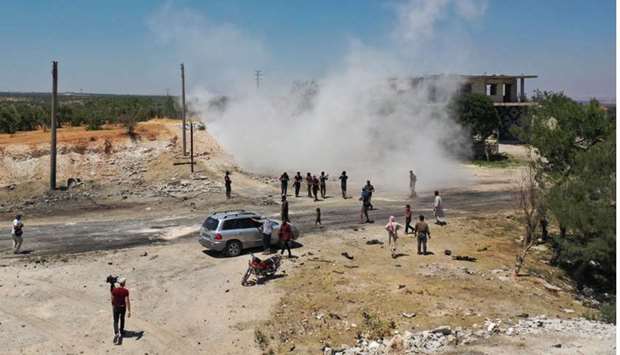 An aerial picture shows Syrians gathering at the site of an improvised explosive device which hit a joint Turkish-Russian patrol on the strategic M4 highway, near the Syrian town of Ariha in the rebel-held northwestern Idlib province