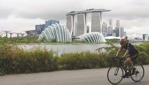 A cyclist rides along Marina Bay overlooking the financial business district in Singapore. The city-stateu2019s economy contracted 12.6 % in April-June, data showed yesterday.