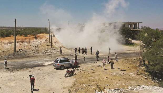 An aerial picture shows Syrians gathering at the site of an improvised explosive device which hit a joint Turkish-Russian patrol on the strategic M4 highway, near the town of Ariha in the rebel-held northwestern Idlib province, yesterday.