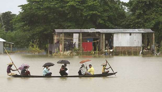 People ride on a boat through flooded waters in Sunamgong.