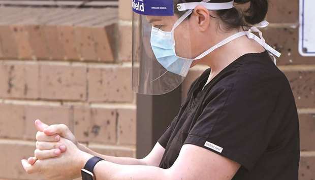 A staff member sanitises her hands outside the Menarock Life aged care facility, where a cluster of some 28 new infections had been reported, in the Melbourne suburb of Essendon yesterday, as the city battles fresh outbreaks of the coronavirus.