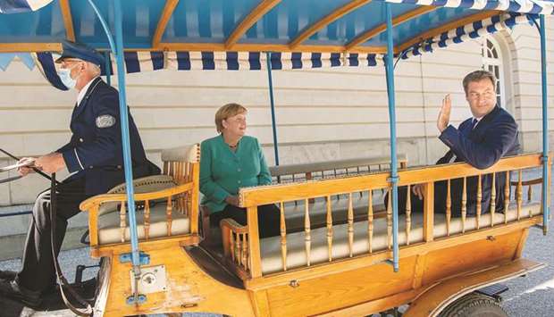 German Chancellor Angela Merkel and Bavariau2019s State Premier and leader of the Bavarian Christian Social Union Markus Soeder are driven on a horse-drawn carriage to the Bavarian cabinet meeting yesterday on Herrenchiemsee island on the lake Chiemsee near Prien Am Chiemsee, Bavaria.