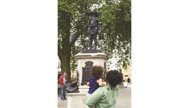 A woman with a child looks at the sculpture of a Black Lives Matter protester standing on the empty plinth previously occupied by the statue of slave trader Edward Colston, in Bristol yesterday.