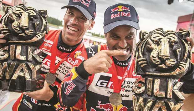 Qataru2019s ace rally driver Nasser al-Attiyah (right) and his co-driver Mathieu Baumel of France celebrate after winning the Silk Way Rally in Dunhuang, China, on July 16, 2019.