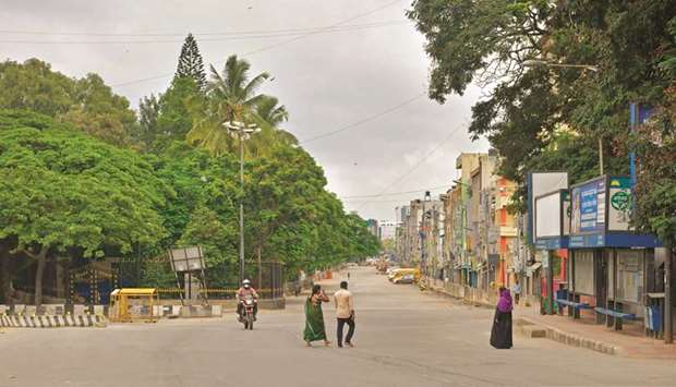 People walk through an empty stretch of a road during a week-long lockdown to contain the surge of coronavirus cases, in Bengaluru yesterday.