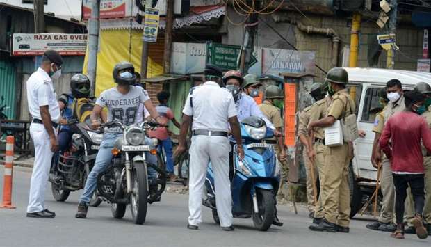 Police personnel stop motorists on a street after a new lockdown was imposed as a preventive measure against the spread of the COVID-19 coronavirus, in Siliguri