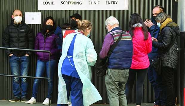 A medical worker speaks to people queueing outside a coronavirus testing venue at The Royal Melbourne Hospital in Melbourne