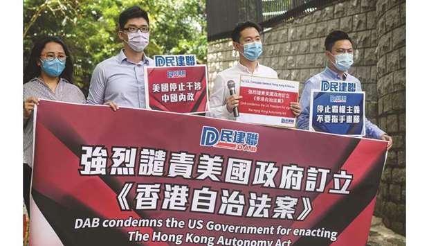 Members of the Democratic Alliance for the Betterment and Progress of Hong Kong (DAB), the largest Pro-Beijing party in the city, hold a banner and placards outside the US Consulate in Hong Kong yesterday, two days after US President Donald Trump signed into law the Hong Kong Autonomy Act, which passed overwhelmingly in Congress as Beijing pushed through a tough national security law in Hong Kong.