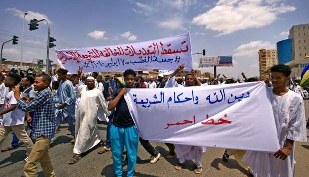 A protester holds up a banner reading in Arabic ,the faith of God and the rulings of Sharia are a red line, while behind him another banner reads ,down with the (constitutional) amendments contrary to Islamic Sharia,, during a demonstration along al-Siteen Street (Sixty) in the Khartoum East district of Sudan's capital.