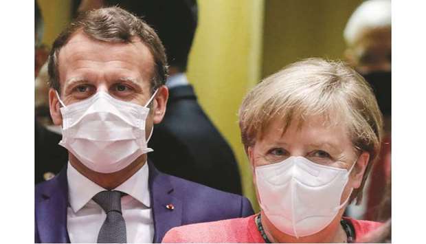 Germanyu2019s Chancellor Angela Merkel stands next to French President Emmanuel Macron prior to the start of the European Union Council in Brussels yesterday, as the leaders of the European Union hold their first face-to-face summit over a post-virus economic rescue plan.