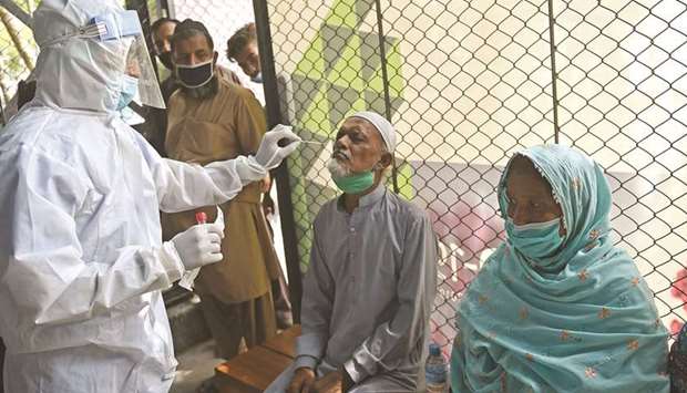 A health official wearing personal protective equipment (PPE) gear takes a swab sample from a man to test for the Covid-19 coronavirus, at a testing point in Karachi, yesterday.