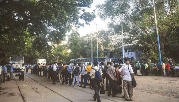 Commuters wait in a queue to catch a bus to return home after a new lockdown was implemented in Kolkata.