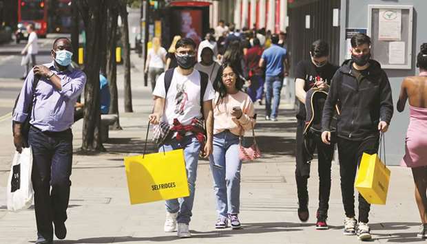 Pedestrians carry shopping bags, amid the coronavirus outbreak, in London yesterday.
