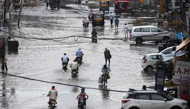 Commuters make their way along a water-logged street following heavy rains in Amritsar, India.