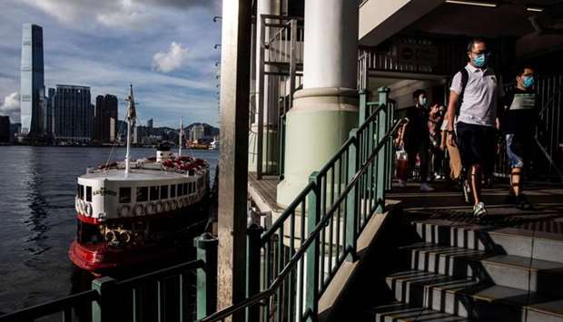 Passangers (R) wearing face masks disembark from a star ferry in Hong Kong