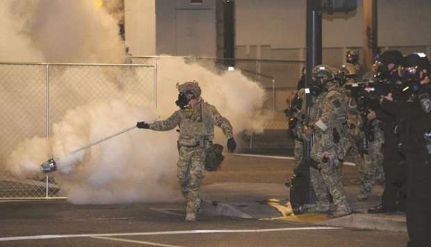 A federal law enforcement officer, deployed under the Trump administrationu2019s new executive order to protect federal monuments and buildings, spreads tear gas during a protest over racial inequality in Portland on Friday night.