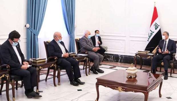 Iraqi Prime Minister Mustafa al-Kadhimi and Iran's Foreign Minister Mohammad Javad Zarif, wearing protective masks, attend a meeting in Baghdad