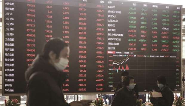 Employees and visitors wearing protective masks walk past an electronic stock board at the Shanghai Stock Exchange (file). The MSCI Asia Pacific Index is set to beat the S&P 500 and the MSCI Europe Index for a second straight month in July as Asia scores high on curbing the virus as well as reopening economies.