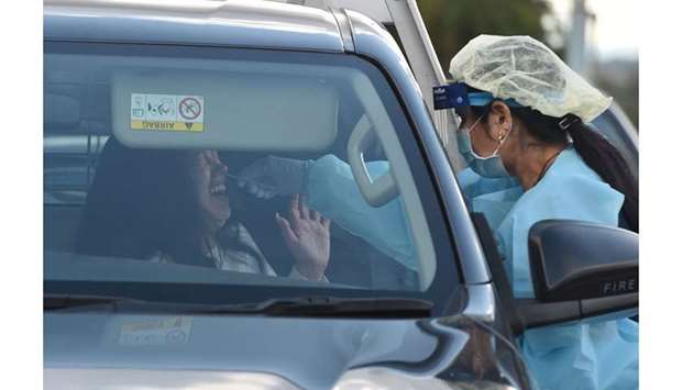 A medical worker (right) tests a woman in her car at a Covid-19 coronavirus testing station in Sydney.