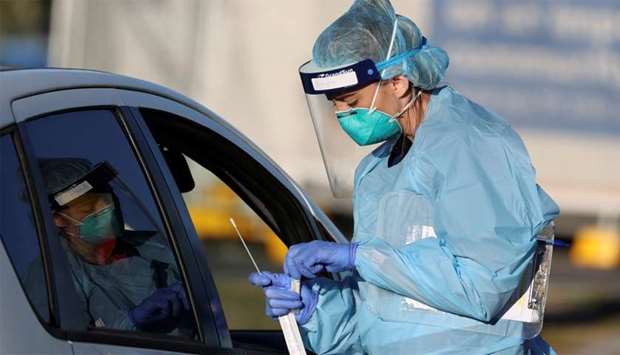 A health worker wearing a protective suit holds a nose-swab sample collected during tests for the coronavirus disease (COVID-19) at the Bondi Beach drive-through testing centre, as the state of New South Wales grapples with an outbreak of new cases, in Sydney, Australia