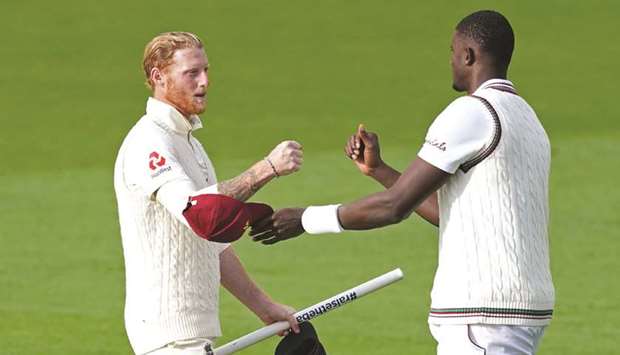 Englandu2019s Ben Stokes (L) fist bumps with West Indiesu2019 Jason Holder on the pitch after England wrapped up the second Test at Old Trafford in Manchester yesterday.
