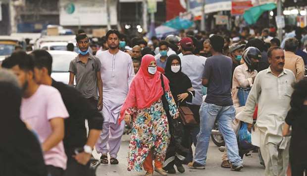 Women wearing protective face masks walk amid the rush of people along a road as the outbreak of the coronavirus continues in Karachi.