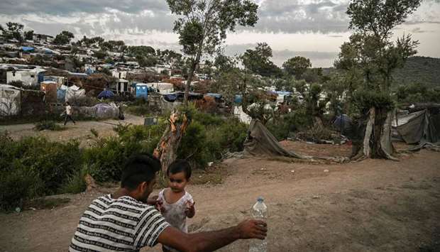 A man with a child is pictured in a improvised tents camp near the refugee camp of Moria in the island of Lesbos on June 21, 2020. Greeceu2019s announcement that it was extending the coronavirus lockdown at its migrant camps until July 5, cancelling plans to lift the measures on June 22, coincided with World Refugee Day on June 27, 2020.