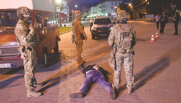 A suspected hostage-taker lies on the ground after being detained by law enforcement officers in the city of Lutsk on Tuesday night.