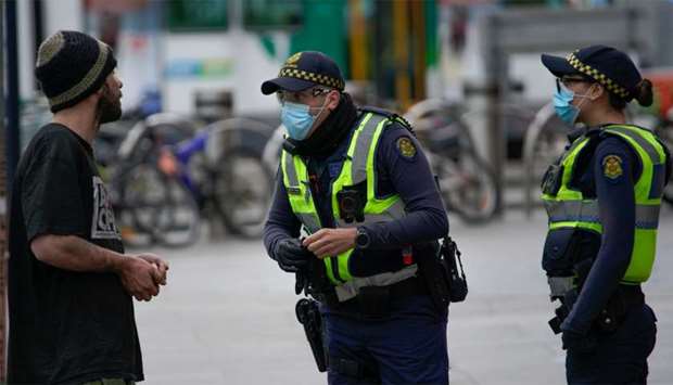 Police officers in protective face masks patrol a street in Melbourne after it became the first city in Australia to enforce mask-wearing in public as part of efforts to curb a resurgence of the coronavirus