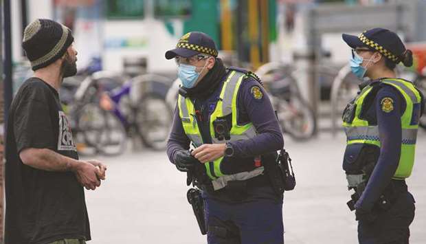 Police officers in protective face masks patrol a street in Melbourne after it became the first city in Australia to enforce mask-wearing in public as part of efforts to curb a resurgence of the coronavirus yesterday.