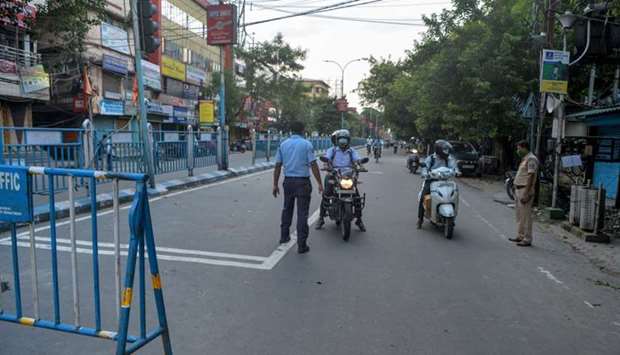 Police personnel stop motorists on a street after a new lockdown has been imposed until July 29 as a preventive measure against the spread of the coronavirus, in Siliguri