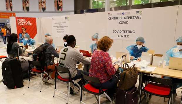 Passengers wearing a mask fullfill documents with healthcare workers for a free Covid-19 test in the arrival hall of Roissy-Charles de Gaulle Airport, north of Paris