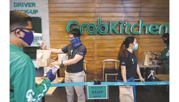 Workers wearing masks for protection against the coronavirus disease (Covid-19) bring out delivery orders at GrabKitchen, in Makati City, Metro Manila, yesterday.