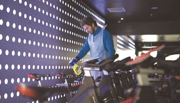 An employee cleans a spin bicycle at a Pure Gym Group health club, as they prepare for reopening today in the City of London. Britainu2019s economy would return to growth in the third quarter after shrinking by more than 25% in March and April, Chris Williamson, chief business economist at PMI compiler IHS Markit, said.