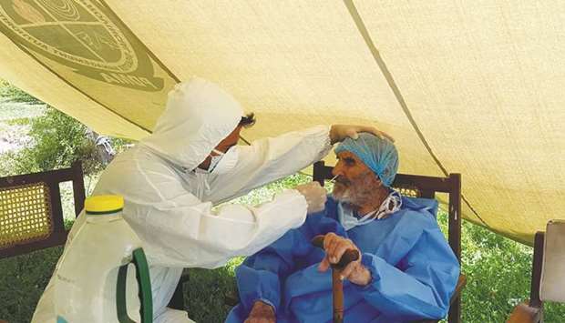 A paramedic wearing protective gear takes a nasal swab of 103-year-old Abdul Alim, to be tested for the coronavirus disease (Covid-19), at the Aga Khan Health Services Emergency Response Centre in Booni, Chitral.
