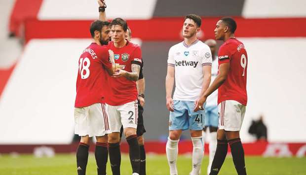 Manchester Unitedu2019s Bruno Fernandes (left) is shown a yellow card by referee during the 1-1 draw against West Ham at Old Trafford in Manchester, United Kingdom, on Wednesday. Failure of United and Chelsea to win on Wednesday means the door is still open for Brendan Rodgersu2019 Leicester, who are fifth in the standings. (Reuters)