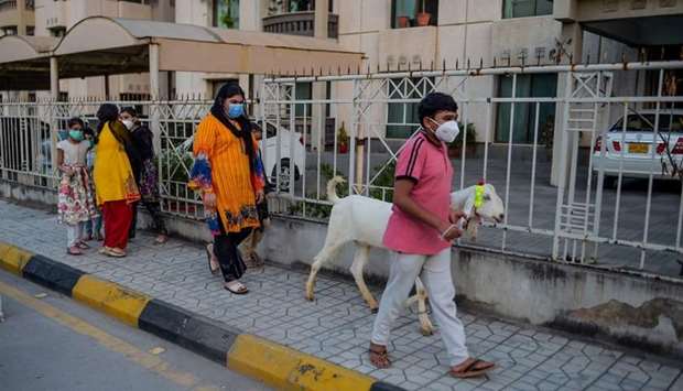 Children wearing face masks walk with a goat ahead of  Eid al-Adha in Rawalpindi