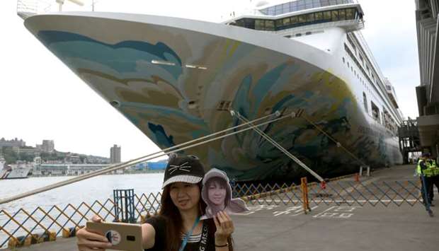 A woman takes a selfie in front of the Explorer Dream cruise ship, in Keelung, Taiwan