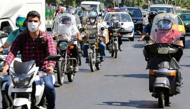 Iranians, wearing protective face masks, ride their motorcycles in the capital Tehran on July 22